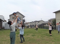 芝生でふれあい遊びをする親子