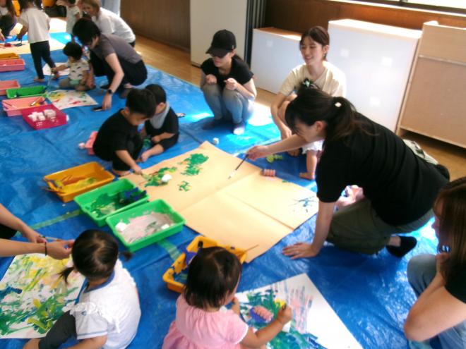 大きな画用紙にローラーで絵の具を塗っている様子